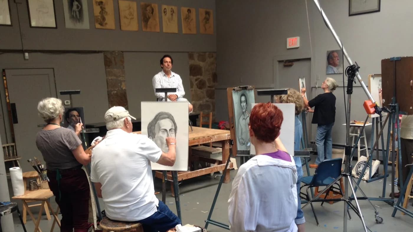 Adult students at easels in a professional drawing class, practising under studio instruction.